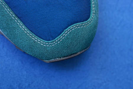 part of one sneaker made of green suede and blue fabric is on the tableの写真素材