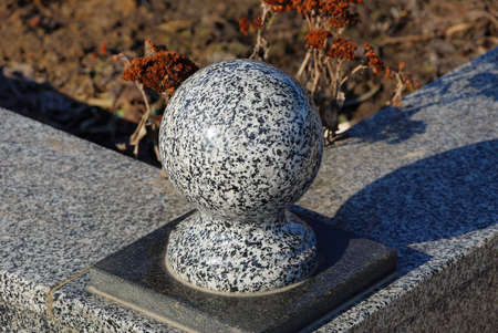 one gray marble ball on a stone fence in a cemeteryの写真素材