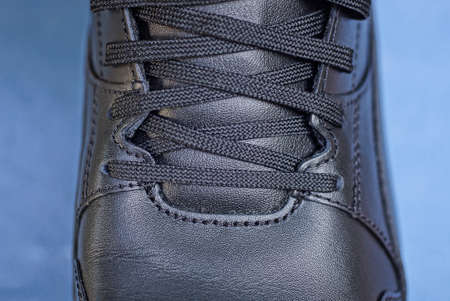 part of one big black leather sneaker on a blue table