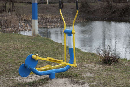 one colored iron sports stationary bike stands on the ground and in green grass on the street on the...