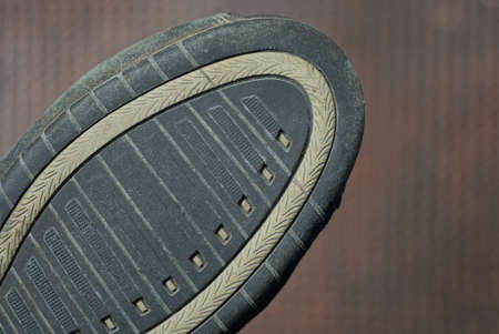 part of one shoe with a black gray sole on a brown backgroundの写真素材