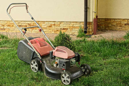 one lawn mower on the green grass near the wall of the building