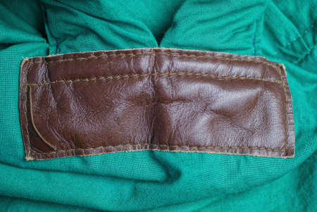 one big brown leather patch texture with stitches on green fabric