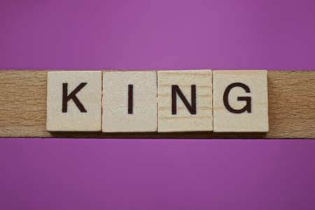 word king made from wooden letters lies on a lilac tableの写真素材