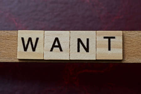 text the word want from gray wooden small letters with black font on an red tableの写真素材