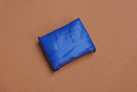 one small box in blue duct tape lies on a brown table