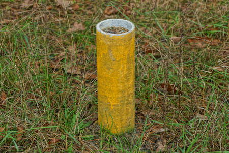 one post limiter made of yellow concrete pipe stands in the green grass outsideの写真素材