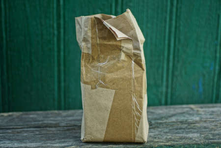 a one large brown full paper bag stands on a green wall