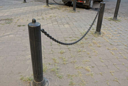 black decorative barrier with iron chains and pillars on the sidewalk on the city street