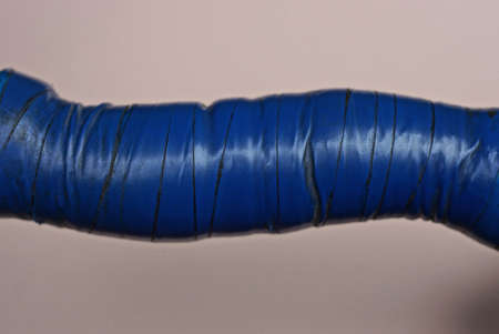 part of an old instrument from a curved handle wrapped in blue electrical tape on a brown backgroundの写真素材