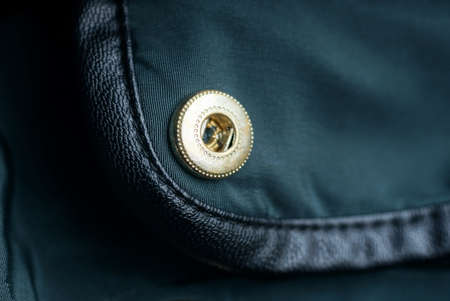 one yellow metal rivet on a green garment fabricの写真素材