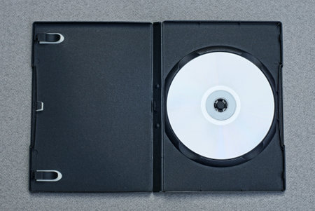 one white CD lies in a black open plastic box on a gray tableの写真素材