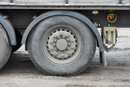 one large dirty wheel on a truck stands on gray asphaltの写真素材