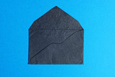 one open black mail envelope made of paper lies on a blue tableの写真素材