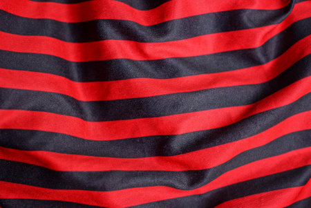 colored texture of crumpled striped synthetic red black fabricの写真素材