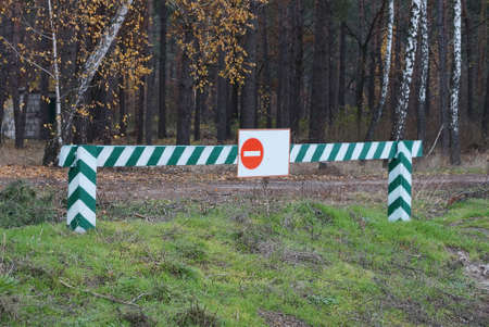 wooden striped barrier with a road sign no entry on the street against the background of pine treesの写真素材