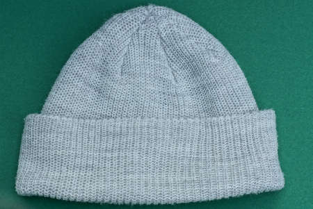 one woolen gray white knitted headdress lies on a green table