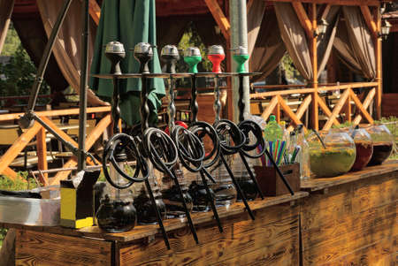a row of black hookahs standing on a brown wooden table of an open summer restaurant on the streetの写真素材