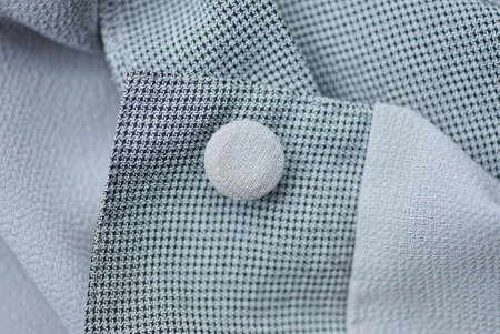 one small white button on gray fabric with a sleeve