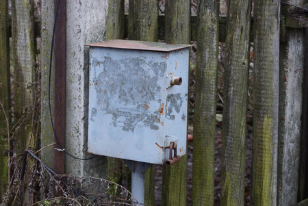one gray metal box against a wooden wall in the street