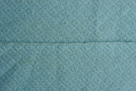 Blue fabric background of a fragment of crumpled cloth and seam