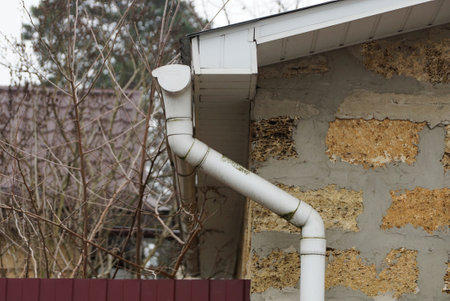 white plastic gutter pipe on brown brick wall outdoorsの写真素材
