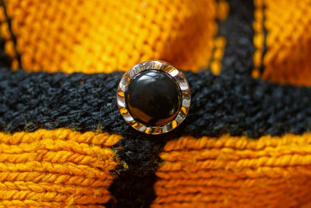 one black plastic button on a yellow woolen garment fabric