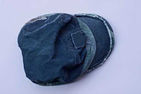 one black crumpled cap made of fabric lies on a pink table