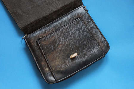 one black open leather bag lies on a blue table