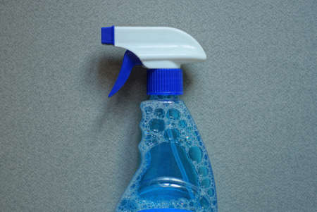 one plastic blue white spray bottle on a liquid bottle on a gray tableの写真素材