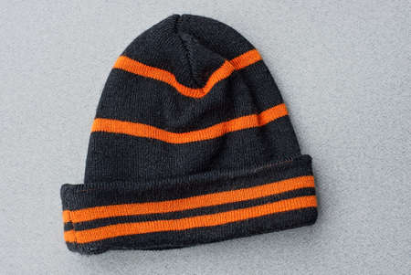 one striped black orange woolen winter hat lies on a gray table