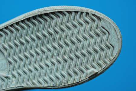 part of a one shoes from a gray white plastic pattern sole on a blue background
