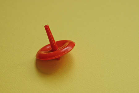 one small red plastic toy whirligig stands on a yellow tableの写真素材