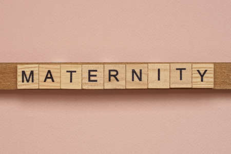 word maternity made of wooden square letters on pink backgroundの写真素材
