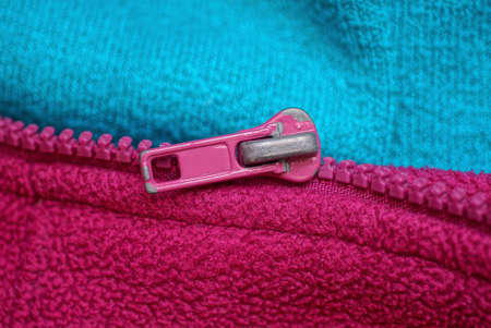 one metal zip on a red blue fabric piece of clothingの写真素材
