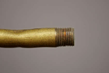 part of one old brown copper tube with thread on gray background