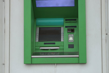 one green electronic atm on a gray wall on the streetの写真素材