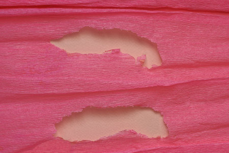 texture of a piece of red crumpled paper with two large brown holesの写真素材