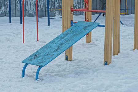 one blue wooden press board on a sports field in snow drifts on a winter streetの写真素材