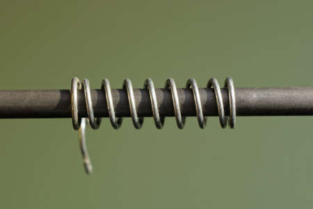 part of a long gray metal rod with an iron spring on a green backgroundの写真素材