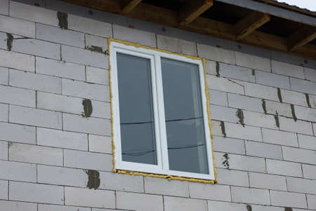 one big white window on the gray brick wall of the house