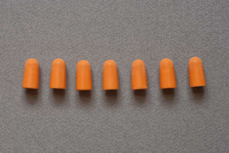 row of orange plastic earplugs on a gray table