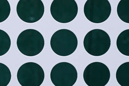 white sheet paper texture with rows of green circular holesの写真素材