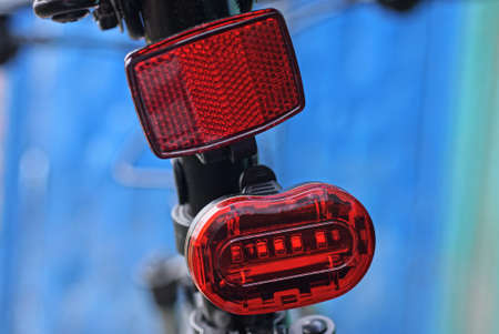red plastic reflector and warning light on black sports bike on blue background