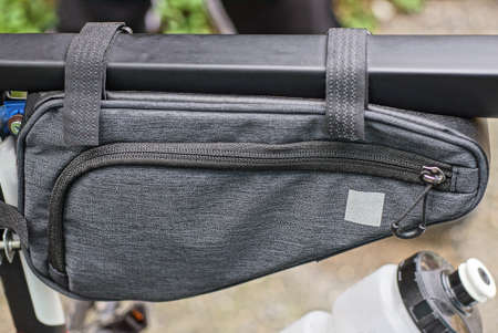 one gray closed fabric glove compartment hangs on a black metal bicycle frame outside