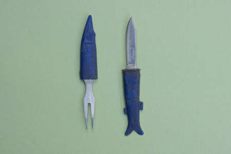 old folding knife and fork with plastic blue handles lie on a gray tableの写真素材
