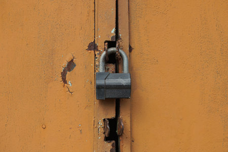 one gray big padlock on a brown iron door