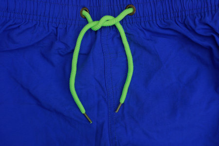 part of blue fabric sweatpants with elastic and long green laces