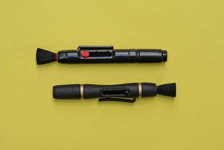 two black long cleaning pencils lies on a yellow table