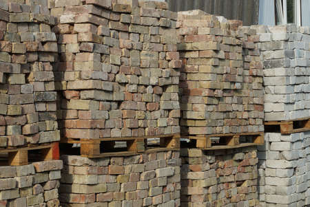 a pile of brown and white bricks on wooden pallets in the street